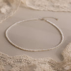 The Summer Pearl Beaded Necklace in Sterling Silver is displayed on a beige lace fabric background, making it the perfect choice for modern pearl jewelry this summer.