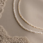The Summer Pearl Beaded Necklace in Sterling Silver rests on beige fabric with lace corners—a modern pearl jewelry piece perfect for summer.