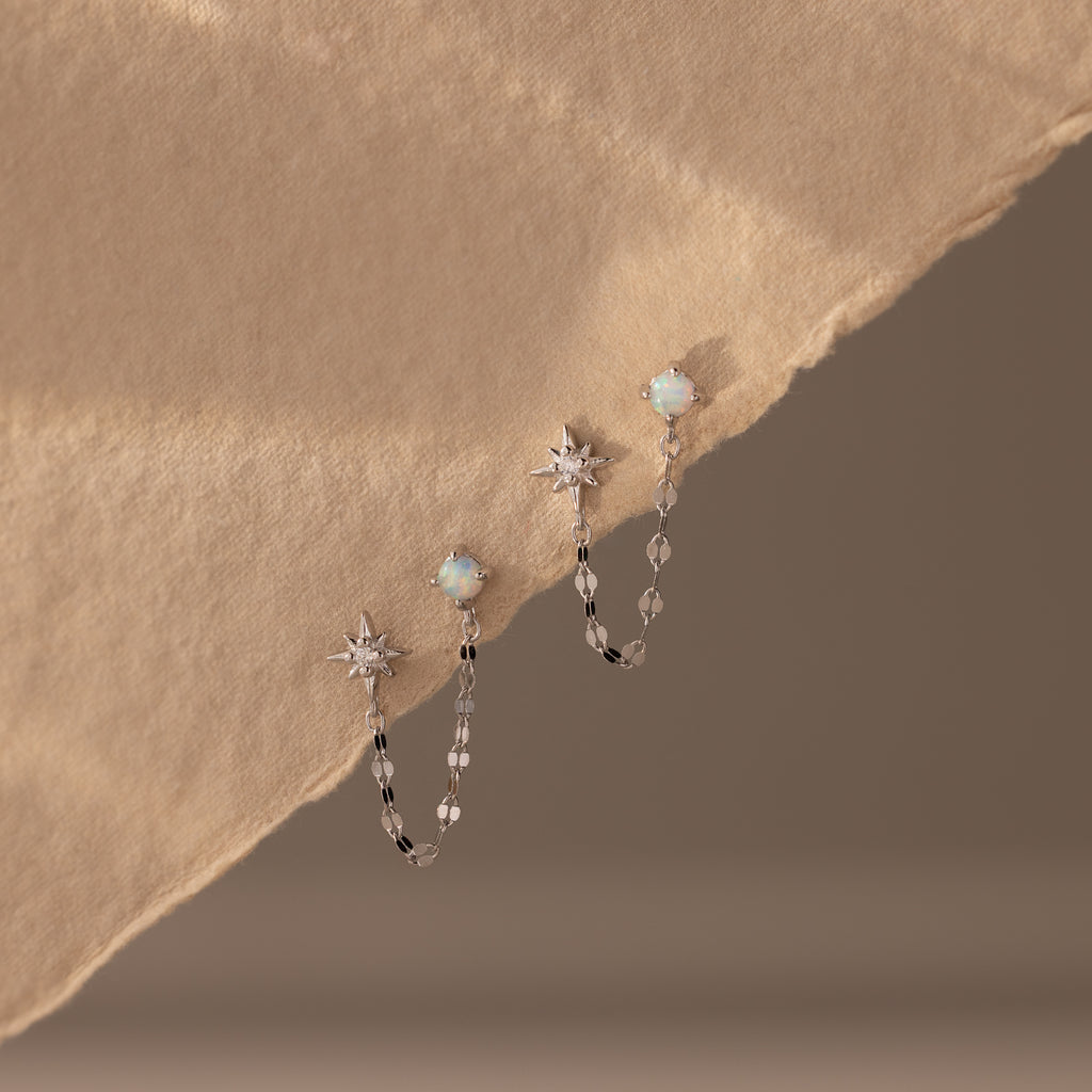 Flatlay of our Opal & Star Duo Chain Studs in Silver against a beige background
