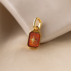 Up close of a red garnet north star charm with a delicate pavé diamond in the center.