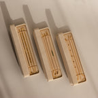 Three beige Bracelet Travel Cases hold delicate gold bracelets and necklaces, casting soft shadows on a light surface.