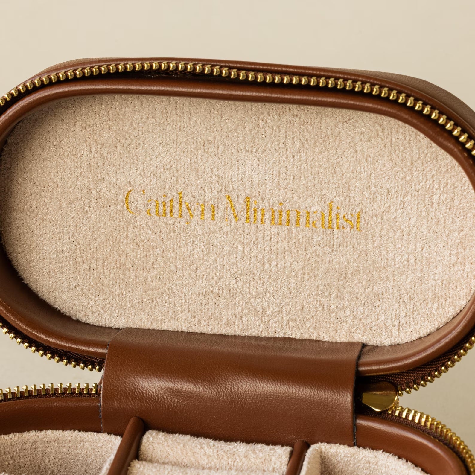 Oval Leather Jewelry Box—compact and stylish with Caitlyn Minimalist in gold on beige suede, perfect as a travel jewelry organizer.