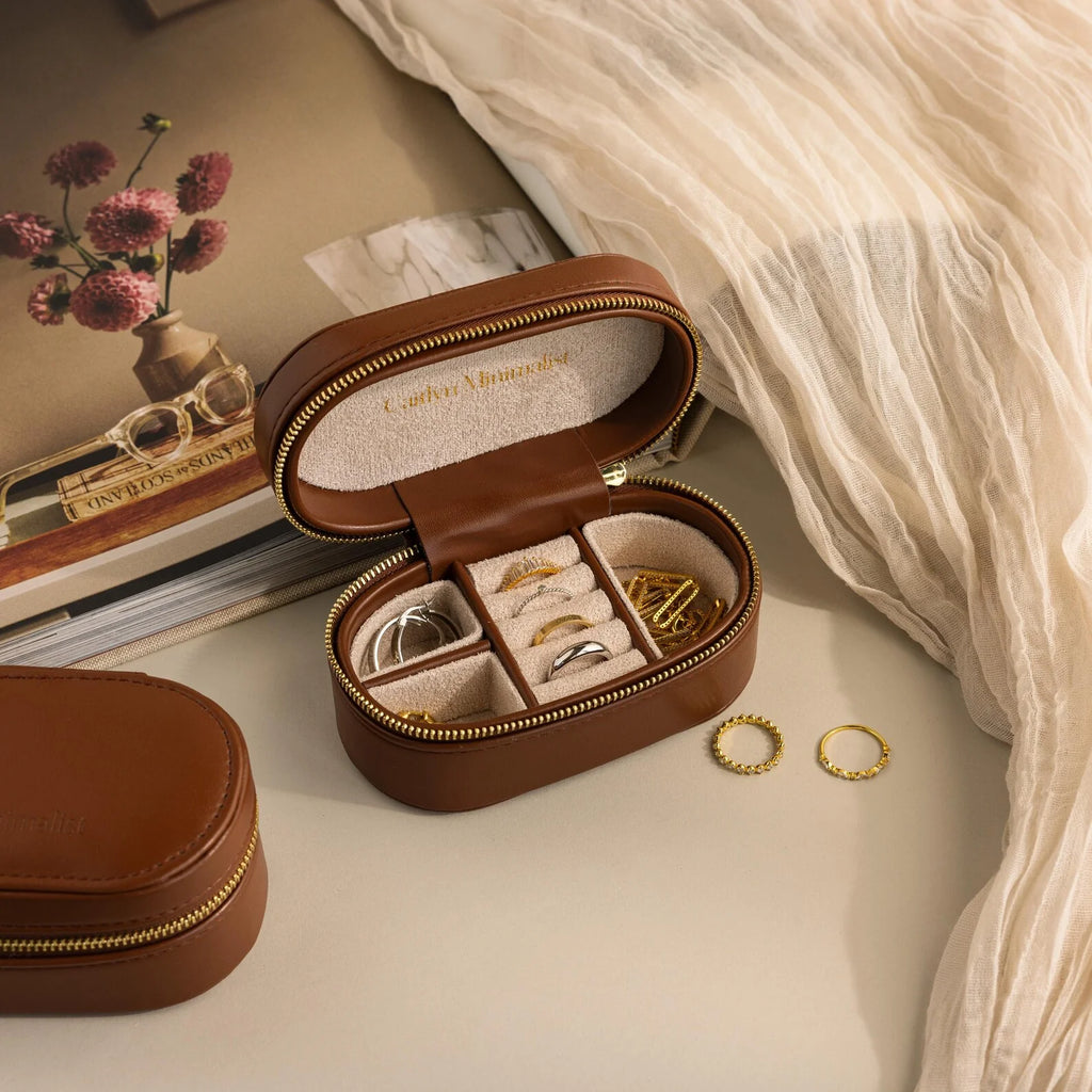 The Corporate Gift Box features a brown leather jewelry case with curated rings, earrings, and necklaces on a beige surface near a book and fabric—ideal for stylish, personalized gifting.
