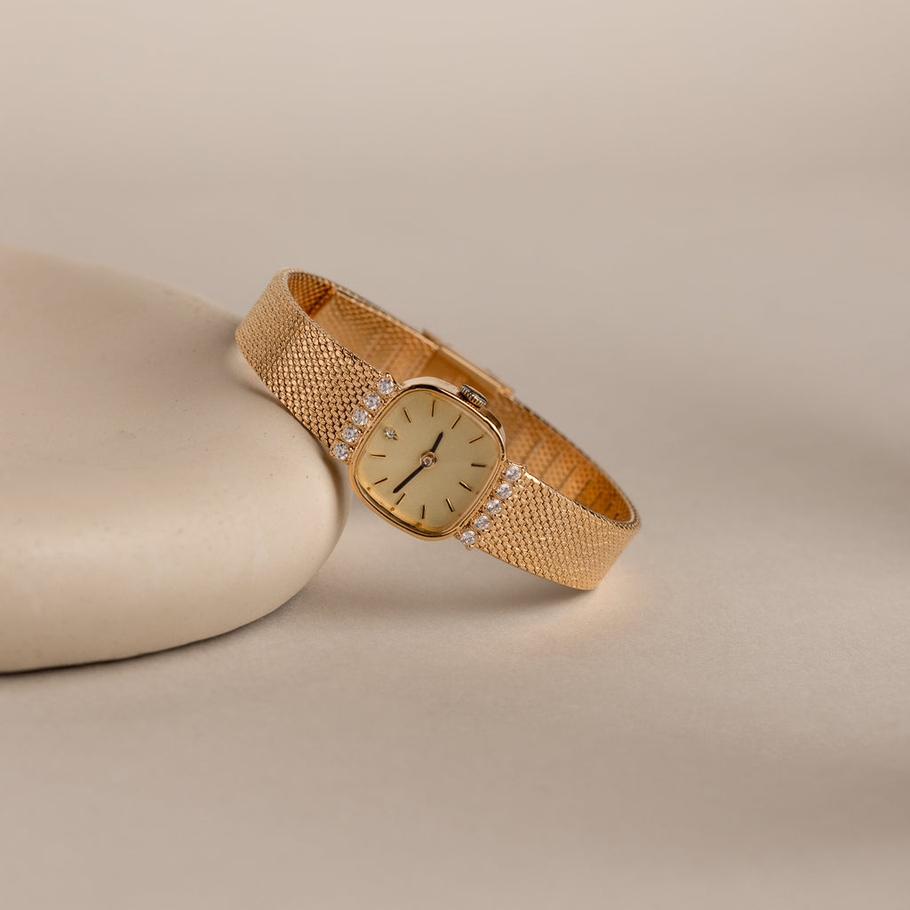 Our Luxe Square Timepiece watch in 18K Gold on a beige background