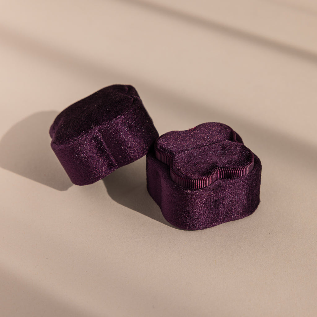 Two Purple Flower Velvet Ring Boxes sit in soft lighting on a beige surface.