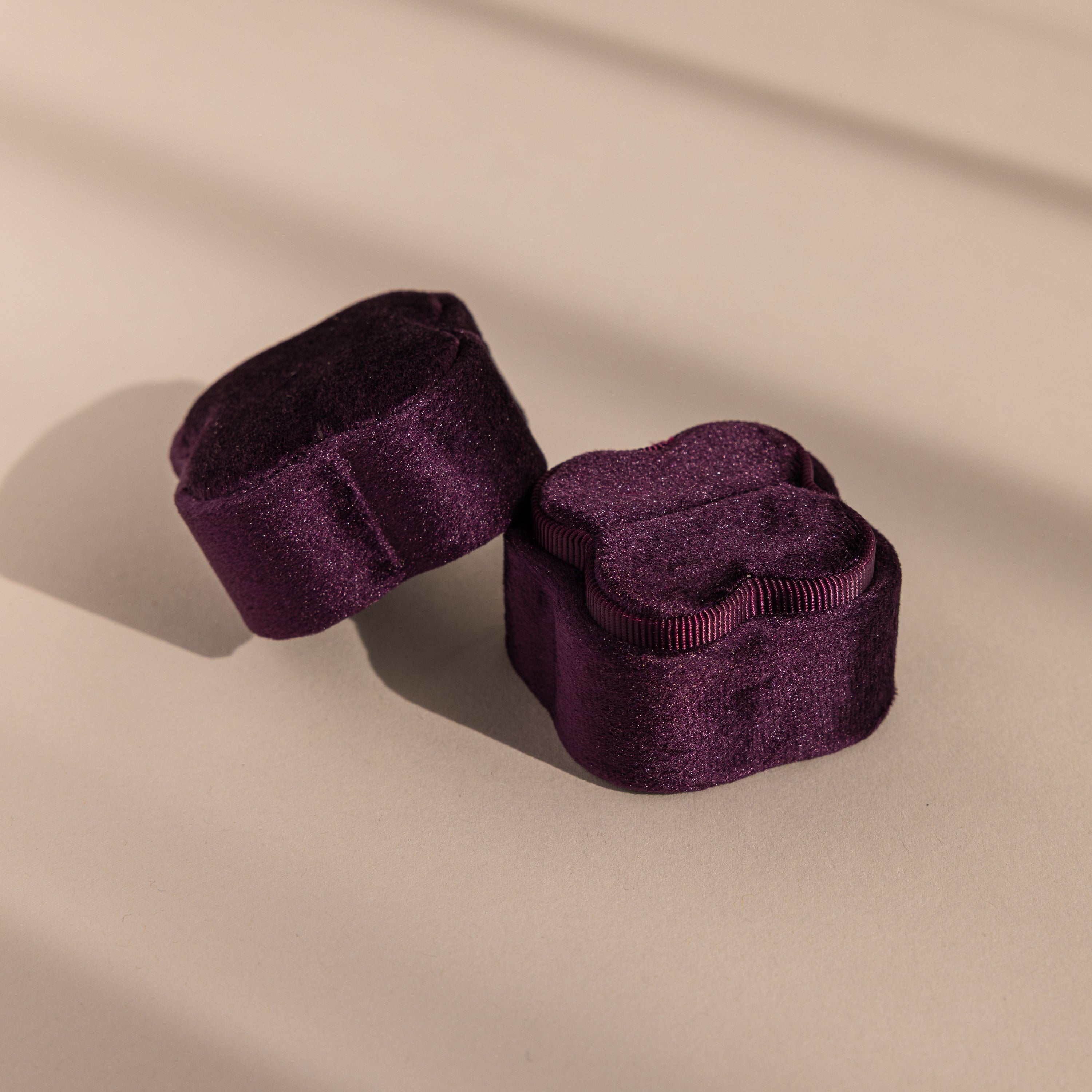 Two Purple Flower Velvet Ring Boxes sit in soft lighting on a beige surface.