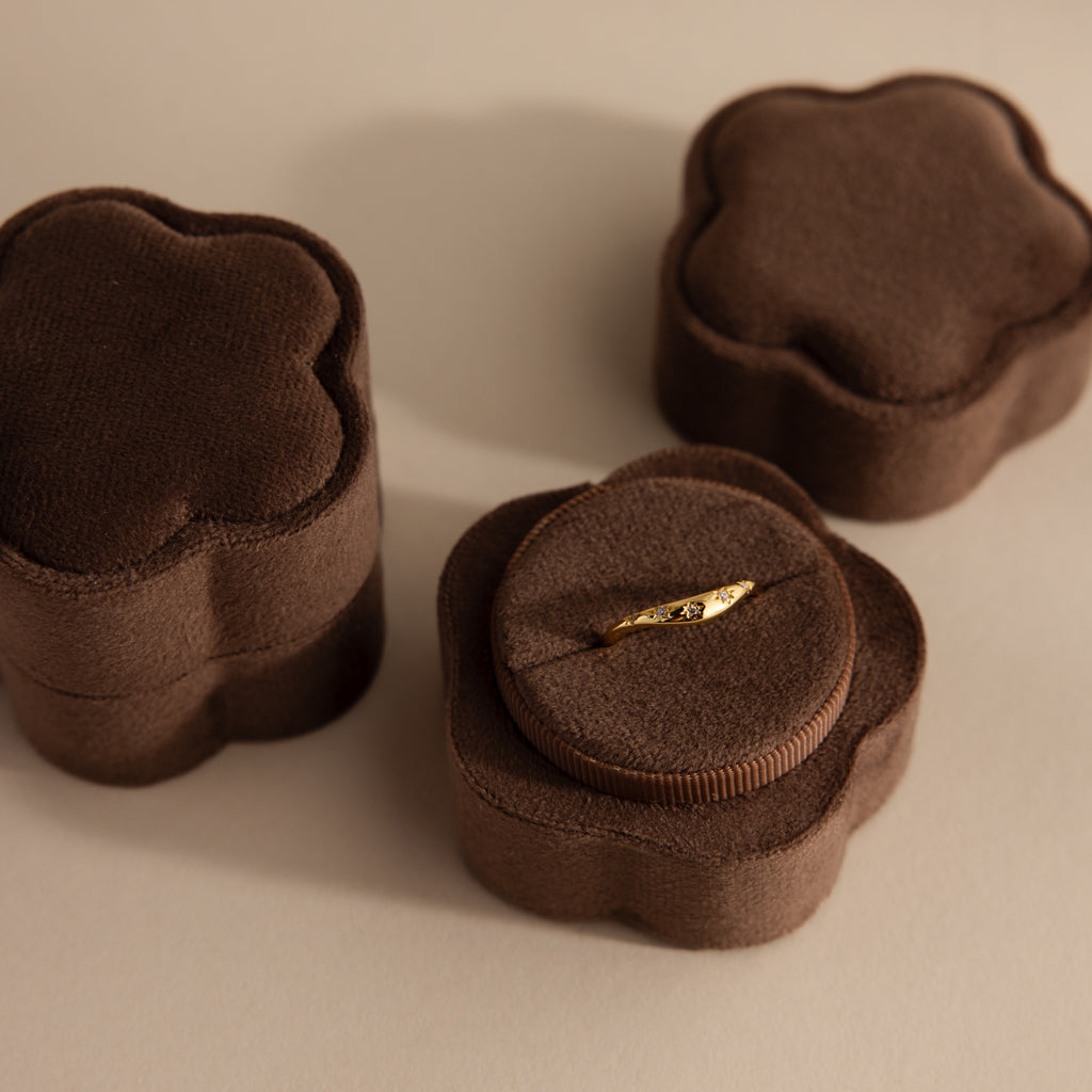 A gold ring displayed in the Brown Flower Velvet Ring Box, with two similar closed boxes beside it.