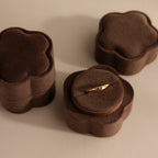 A gold ring displayed in the Brown Flower Velvet Ring Box, with two similar closed boxes beside it.