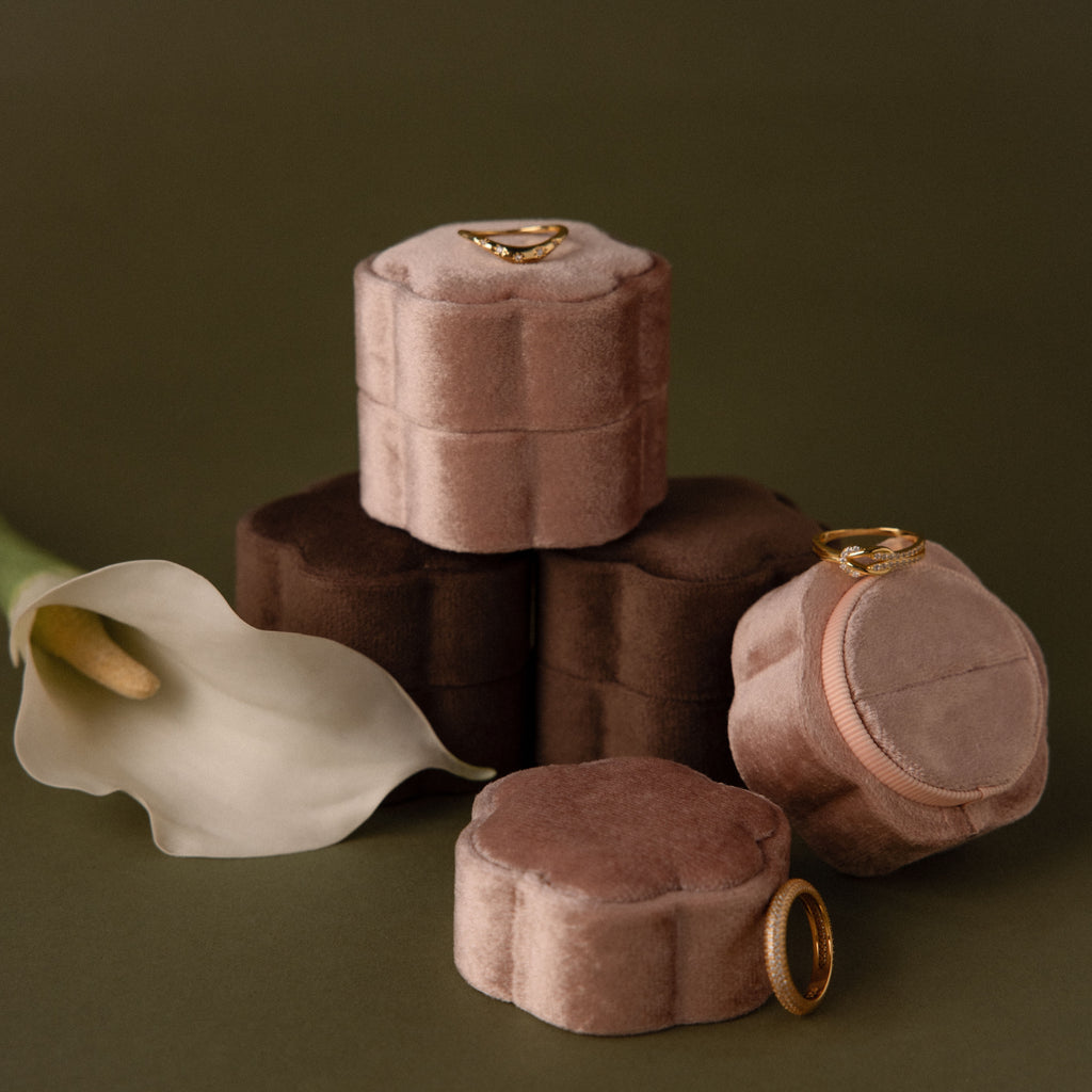 The Pink Flower Velvet Ring Box, in soft brown and pink velvet with gold rings, sits beside a white calla lily—an elegant choice for a proposal ring box.