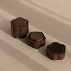 Three Brown Flower Velvet Ring Boxes, featuring a floral design and velvet finish, are arranged on a beige surface with soft shadows.
