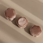 Three plush, flower-shaped puffs in soft brown tones are arranged on a beige surface, their appearance reminiscent of the Pink Flower Velvet Ring Box.