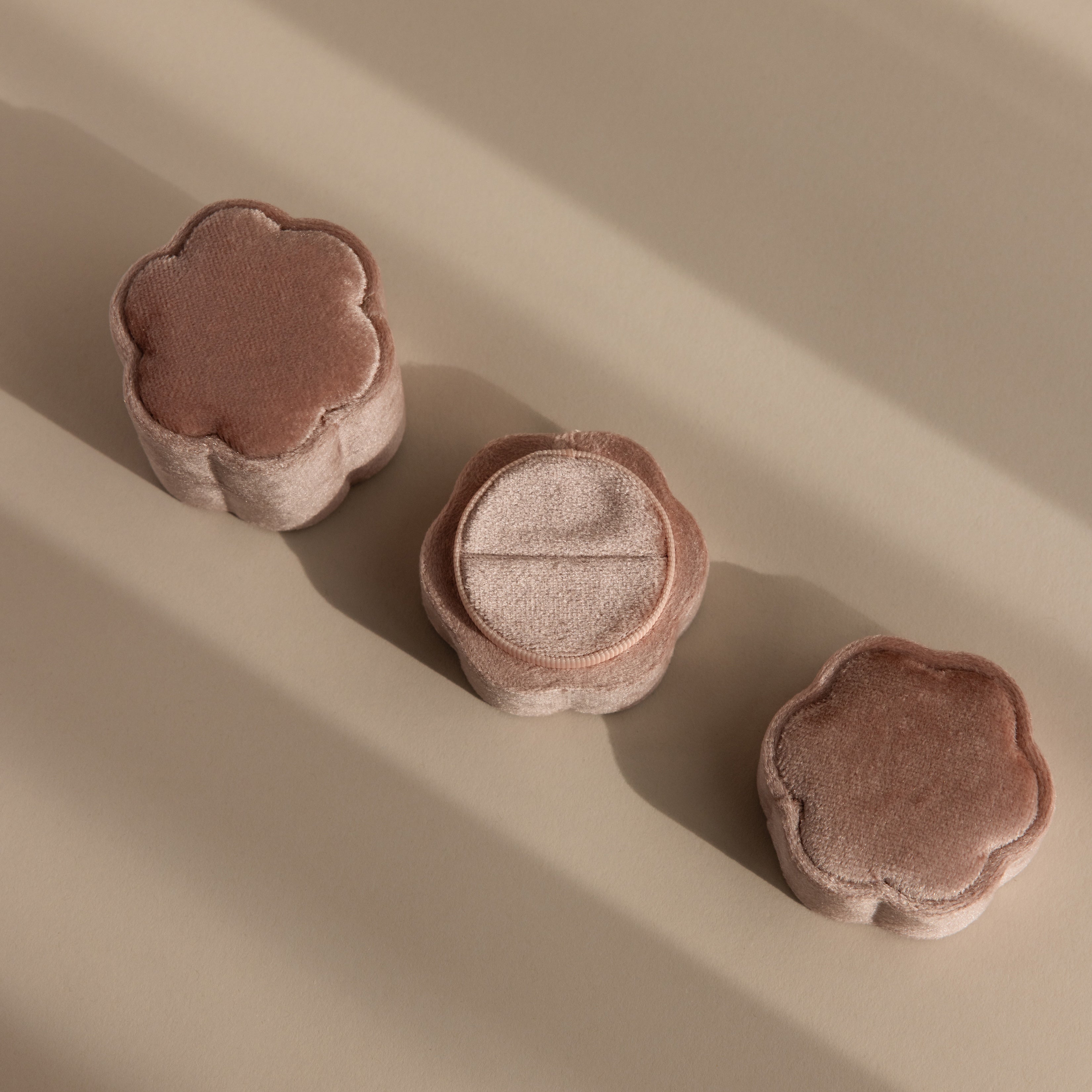 Three plush, flower-shaped puffs in soft brown tones are arranged on a beige surface, their appearance reminiscent of the Pink Flower Velvet Ring Box.