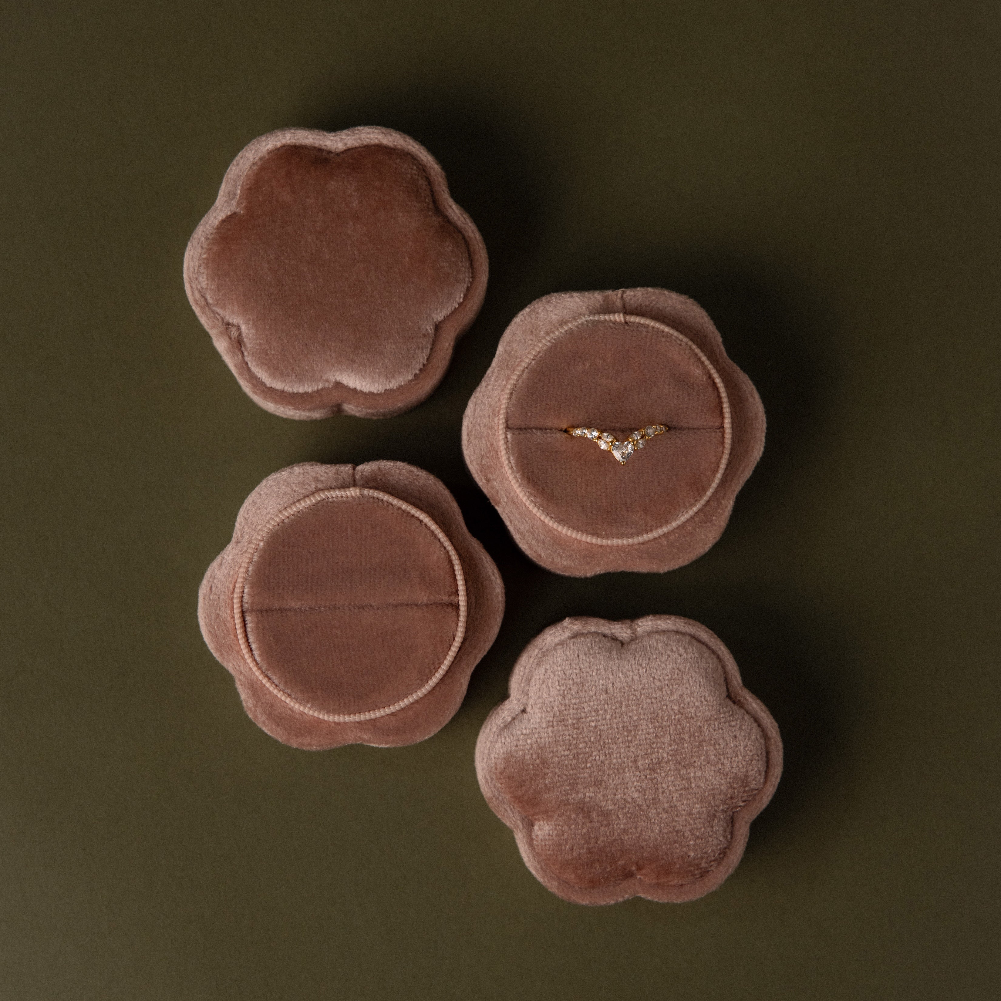 Four Pink Flower Velvet Ring Boxes, one open to reveal a delicate diamond ring, arranged on an olive background.