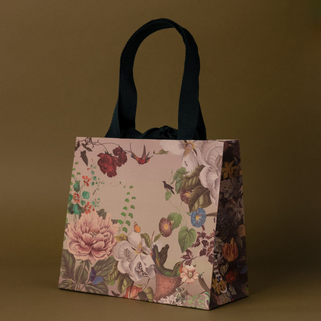 The Floral Gift Bag Add-On features a floral design with black handles on an olive-green background—an elegant way to wrap gifts and add a special touch to any present.