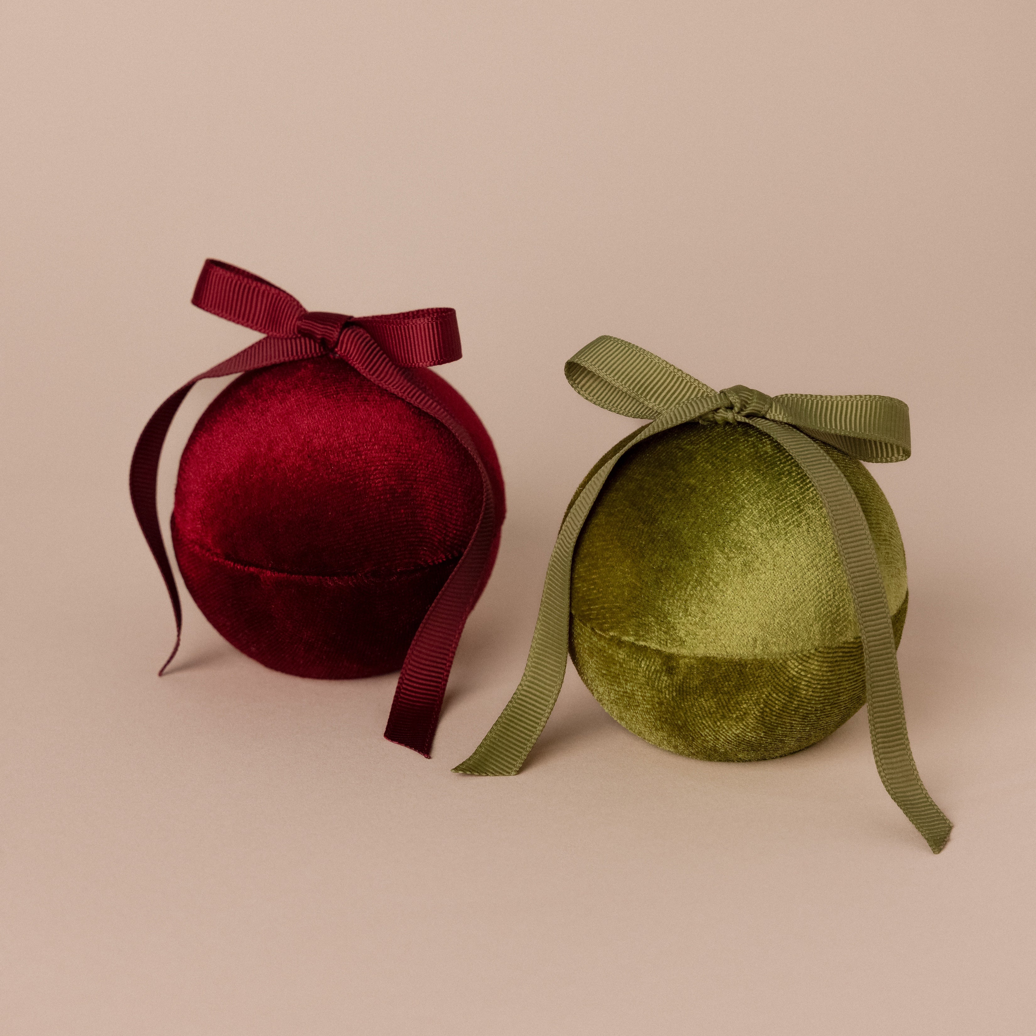A Red Velvet Round Ring Box with a matching ribbon bow on top sits on a beige background.