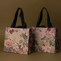 The Floral Gift Bag Add-On features two elegant floral-patterned gift bags with black handles, displayed on a simple olive green background.