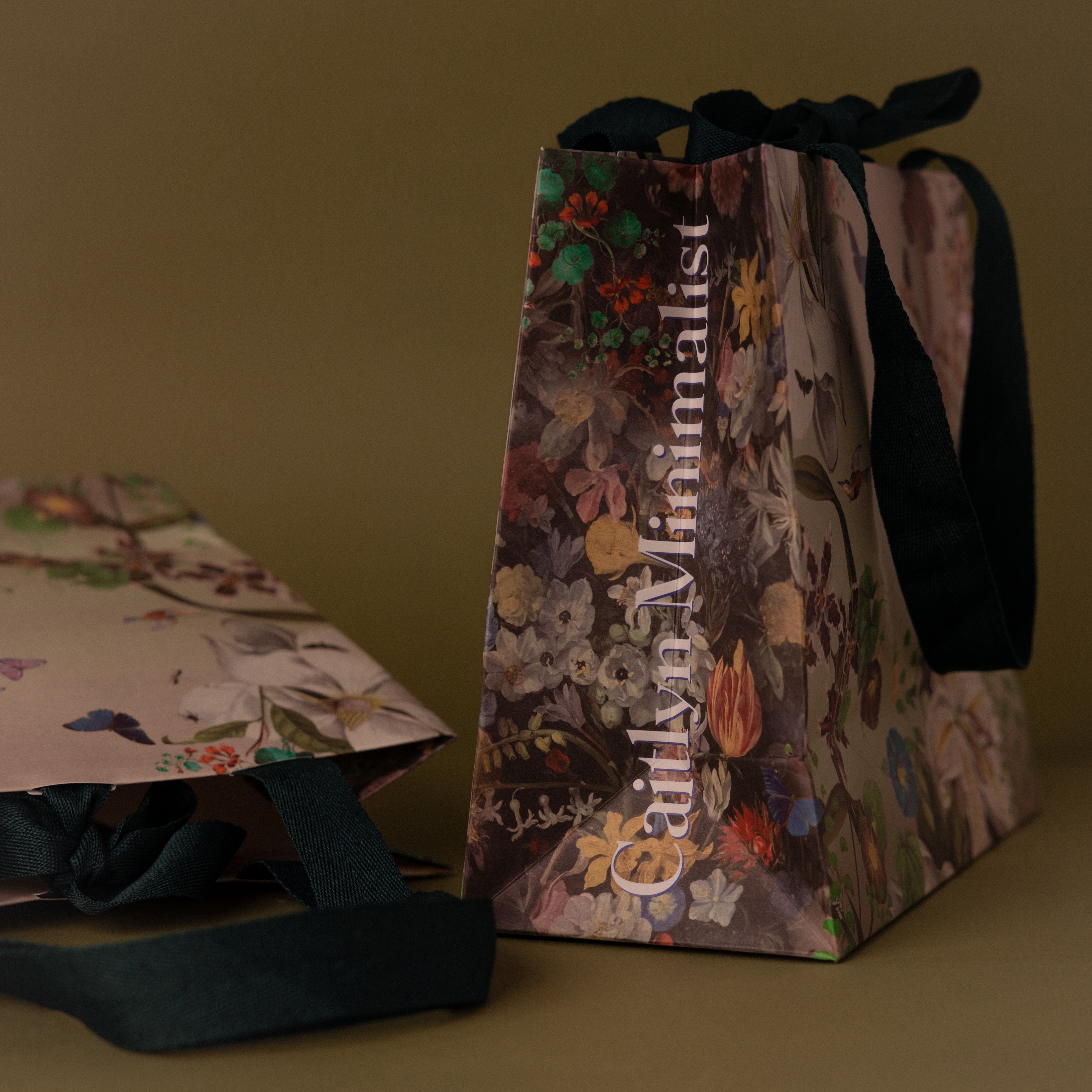 The Gift Wrap Add-On features floral gift bags with black ribbon handles on a brown surface—an elegant choice that adds a special finishing touch to any present.