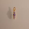 The Ombre Lace Amethyst Charm features five vertically arranged purple gemstones and casts a shadow on a beige background—an ideal personalized birth month gift.