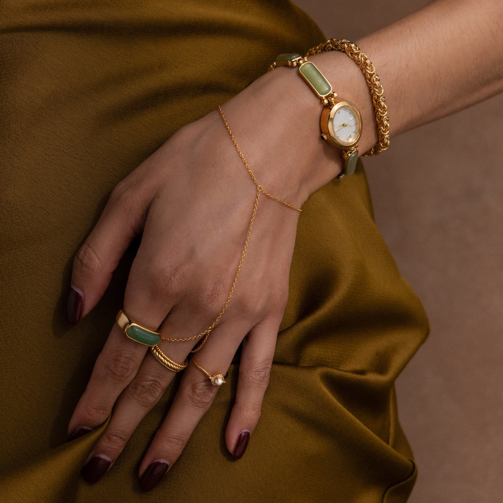A hand adorned with a Bold Byzantine Bracelet rests gracefully on silky brown fabric.