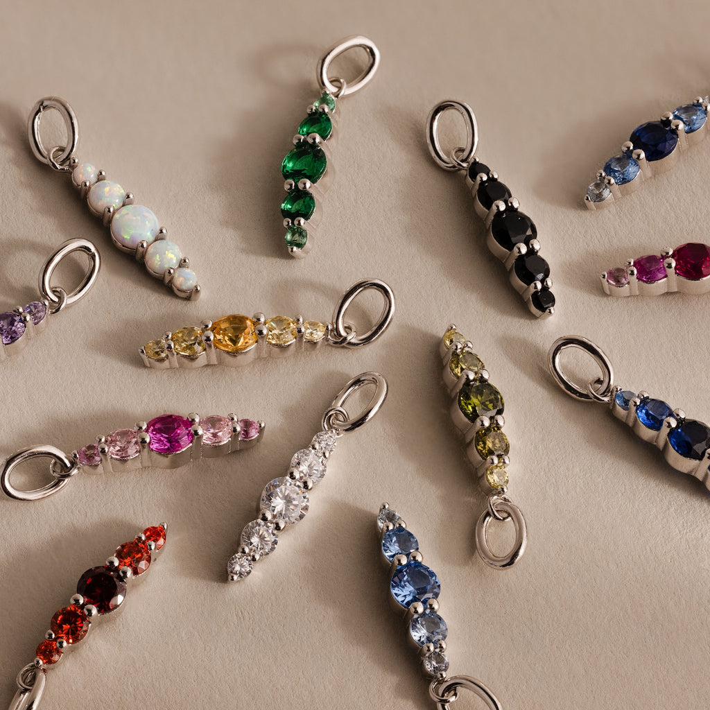 The Ombre Lace Amethyst Charm, featuring a silver loop, shines among assorted gemstone charms—perfect for a unique personalized accessory or thoughtful birth month gift.