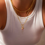 Person wearing layered gold necklaces and a white ribbed tank top, with one necklace featuring the Ombre Lace Birthstone Charm.