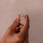 A hand holds the Dainty Ribbed Opal Ring, featuring an elegant opal stone, decorative accents, and a ribbed band against a neutral background.