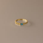 The Dainty Ribbed Blue Zircon Ring features a textured band and a small rectangular blue zircon gemstone, ideal as a birthstone piece or for stacking. Shown on a neutral background.