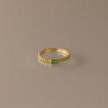 The Dainty Ribbed Emerald Ring features a small green rectangular emerald at its center, perfect for stacking and adding a touch of elegance to any look.
