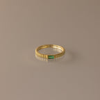 The Dainty Ribbed Emerald Ring features a small green rectangular emerald at its center, perfect for stacking and adding a touch of elegance to any look.