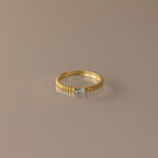 The Dainty Ribbed Aquamarine Ring features a gold band with a rectangular aquamarine gemstone at its center, shown against a neutral background.