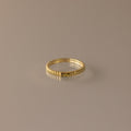 The Dainty Ribbed Peridot Ring features a gold, ribbed design and a minimalist look, displayed on a neutral background—perfect for stacking and adding elegant style to any outfit.