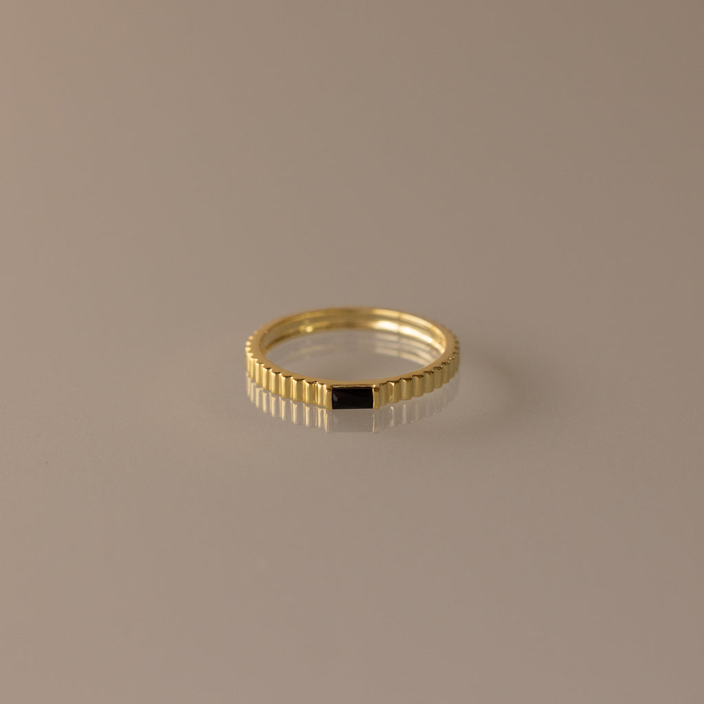 The Dainty Ribbed Onyx Ring features a thin gold band with a subtle ridged design and a small black rectangular onyx detail, shown against a neutral background.