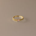 The Dainty Ribbed Pink Tourmaline Ring features a rectangular pink tourmaline gemstone at the center and a ribbed gold band, shown against a neutral background.