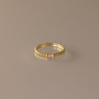 The Dainty Ribbed Pink Tourmaline Ring features a rectangular pink tourmaline gemstone at the center and a ribbed gold band, shown against a neutral background.