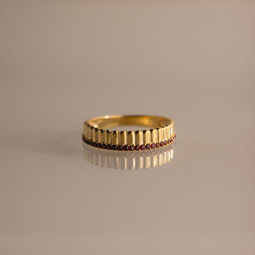 Ribbed Garnet Stack Ring with a ridged design and a row of small red garnets, ideal for stacking with your favorite rings. Shown on a neutral background.