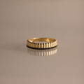 The Ribbed Onyx Stack Ring is a modern stackable ring with a gold ribbed band and a row of small black onyx stones set around the center.