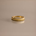 The Ribbed Peridot Stack Ring features a gold ribbed texture with a row of small yellow-green peridot stones, perfect as a modern stackable accessory. Shown against a neutral background.