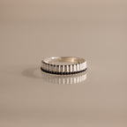 The Ribbed Onyx Stack Ring features a silver ribbed band with a row of small dark onyx stones, displayed on a neutral background.