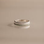 A modern stackable ring, the Ribbed Aquamarine Stack Ring showcases a row of small aquamarine gemstones, elegantly displayed on a beige reflective surface.