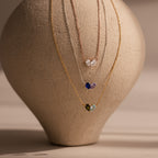 The Toi et Moi Teardrop Heart Necklace and two other delicate necklaces are draped over a textured beige vase.