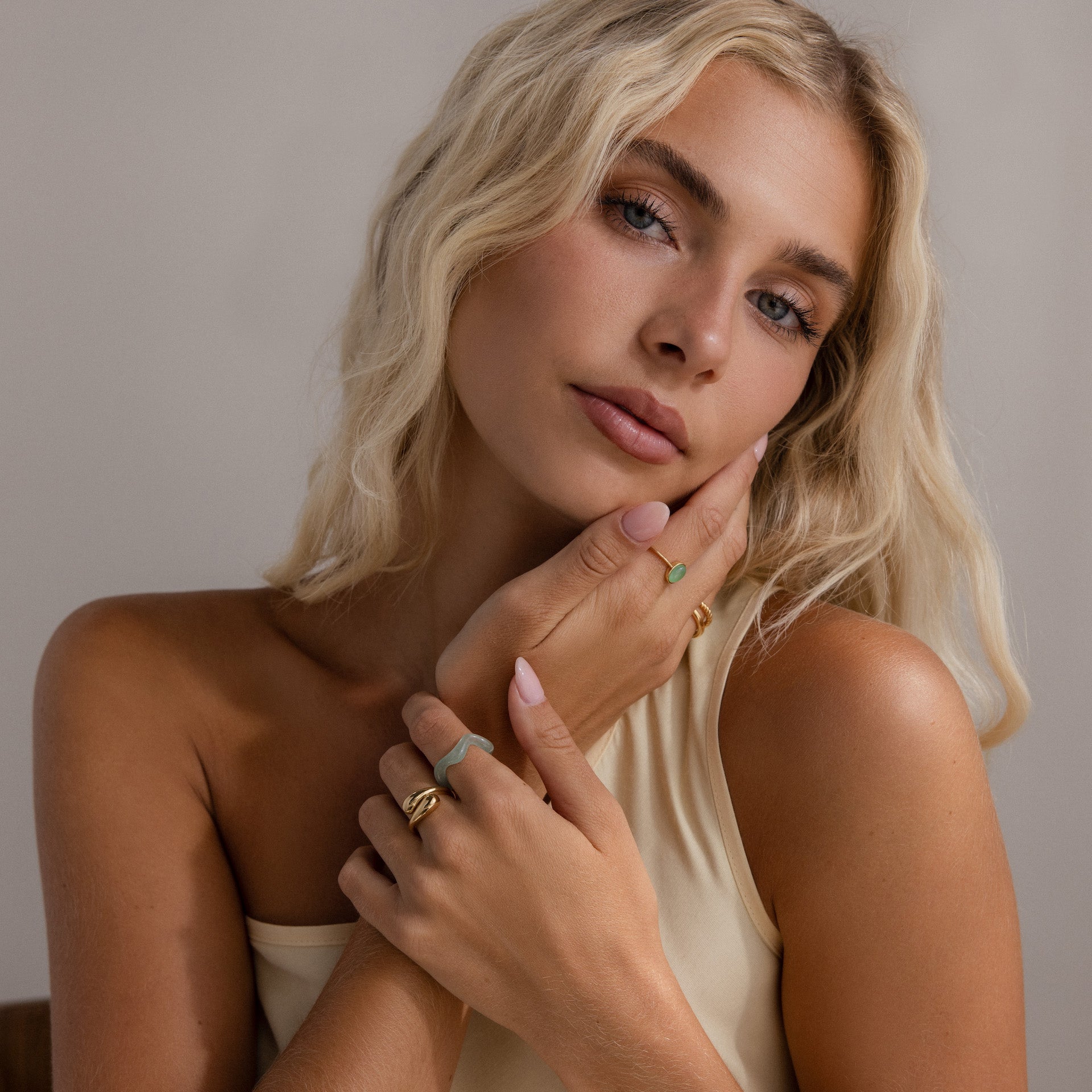 Model wearing the Jade Wave Ring, styled with multiple gold and green jade rings.