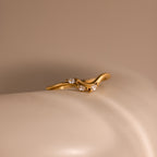 Gold curve marquise diamond ring featuring three marquise cut diamonds displayed on a smooth neutral surface.