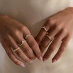Gold pavé diamond ring on hand, featuring a curved band with shimmering pavé diamonds, styled alongside three other gold diamond rings.