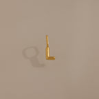 The Bubble Letter Charm in 18K Gold, shaped like an 'L', casts a shadow on a neutral background—a stylish, personalized jewelry piece ideal as a charm for a bracelet or necklace.
