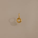 The Bubble Letter Charm in 18K Gold features a gold circular design with a small loop, shown casting a shadow on a beige background—ideal as a bracelet charm or for personalized jewelry.