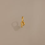 The Bubble Letter Charm in 18K Gold shaped like the letter P rests on a plain beige background, making it an ideal personalized jewelry piece or trendy charm for bracelet lovers.