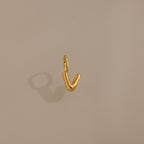 The Bubble Letter Charm in 18K Gold shines with a smooth, V-shaped design on a beige background—ideal as a personalized jewelry accent for bracelet lovers.