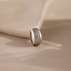 The Bold Pave Dome Charm in Silver features rows of sparkling small diamonds on a soft beige fabric background, adding timeless sophistication to any look.