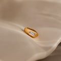The Baguette Diamond Charm in 18K Gold shines with timeless elegance as it rests on a softly textured beige surface—an ideal choice for anyone seeking a refined and classic jewelry piece.
