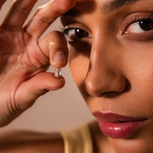 Close-up of a woman holding the Baguette Diamond Charm in Silver near her face, showcasing its detail and brilliance—perfect for highlighting this sparkling silver jewelry piece with diamond accents in SEO-driven product descriptions.